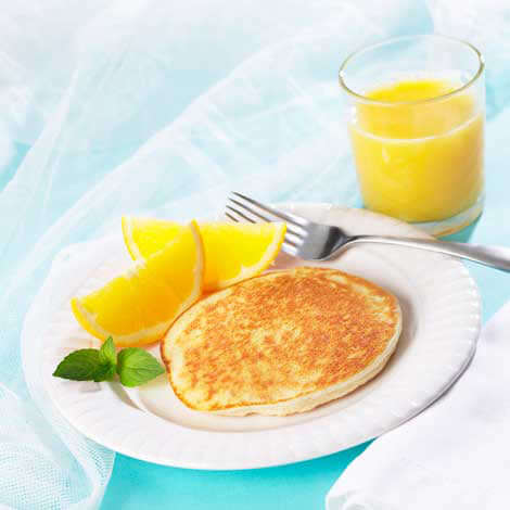 Delicious protein pancakes served with orange slices and a refreshing glass of orange juice.